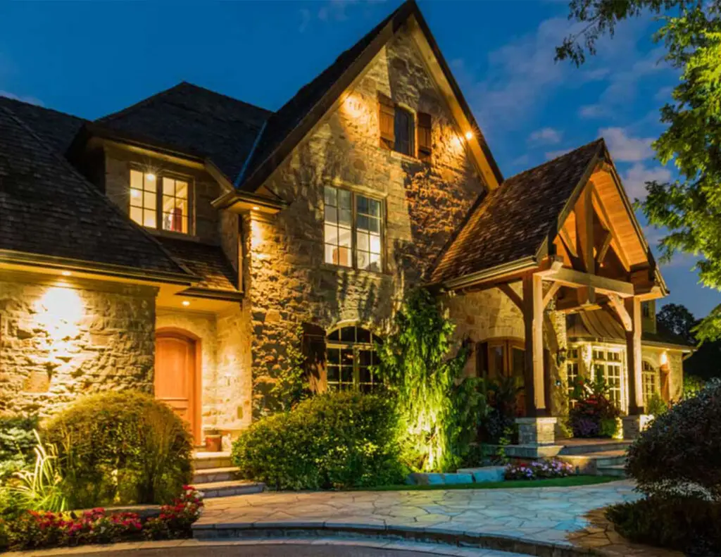 Custom landscape lighting design on luxury stone home exterior at night Toronto, Phaze-In Electric Ltd.